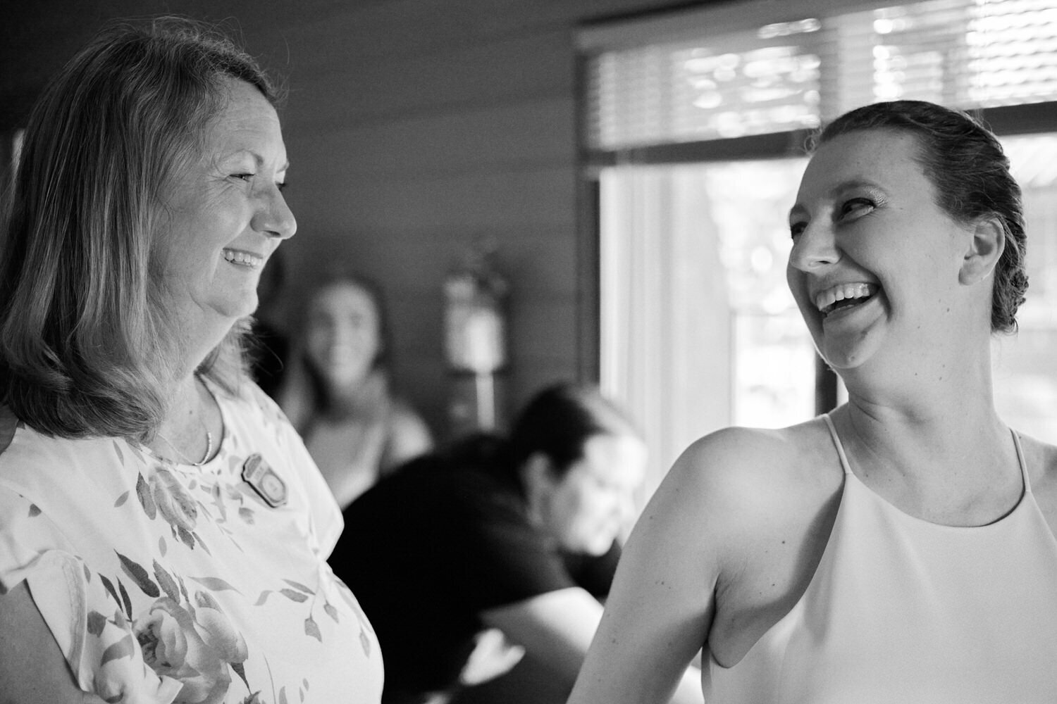 Bride turns around to smile at her mother after putting on her dress