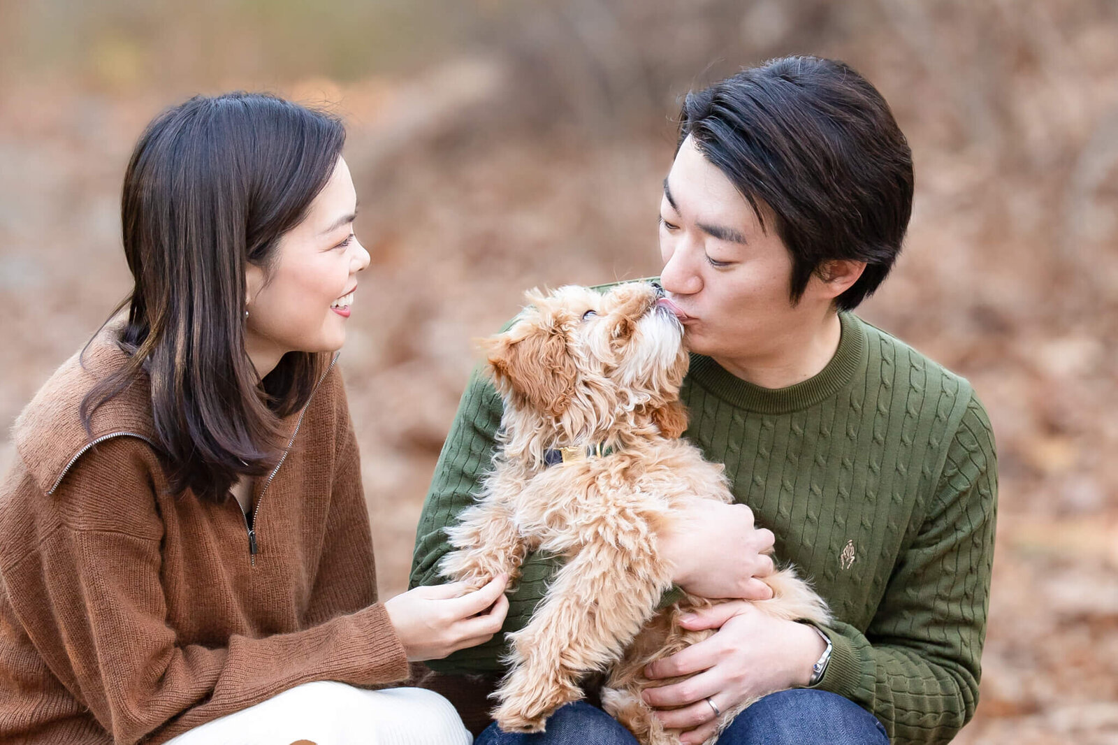 Beautiful Asian puppy Mom smiling at her Golden Doodle puppy kissing her husband