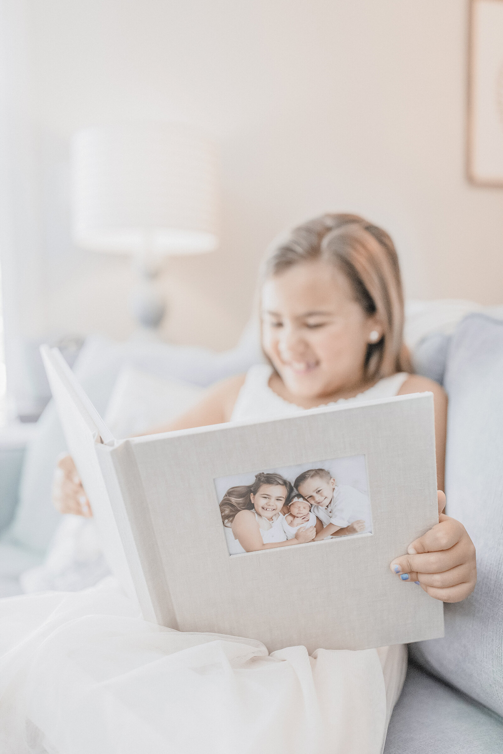 Little girl looking at album on couch smiling