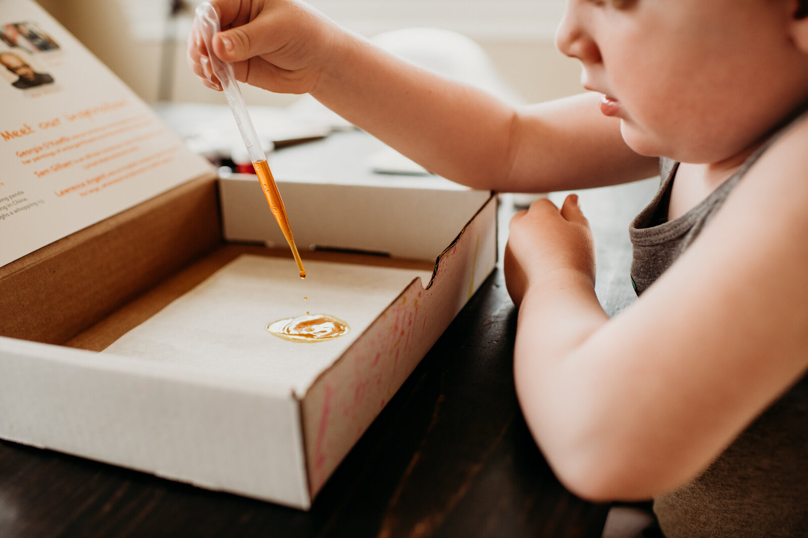 Branding Photographer,  a boy uses a dropper to drop colored water into a craft box