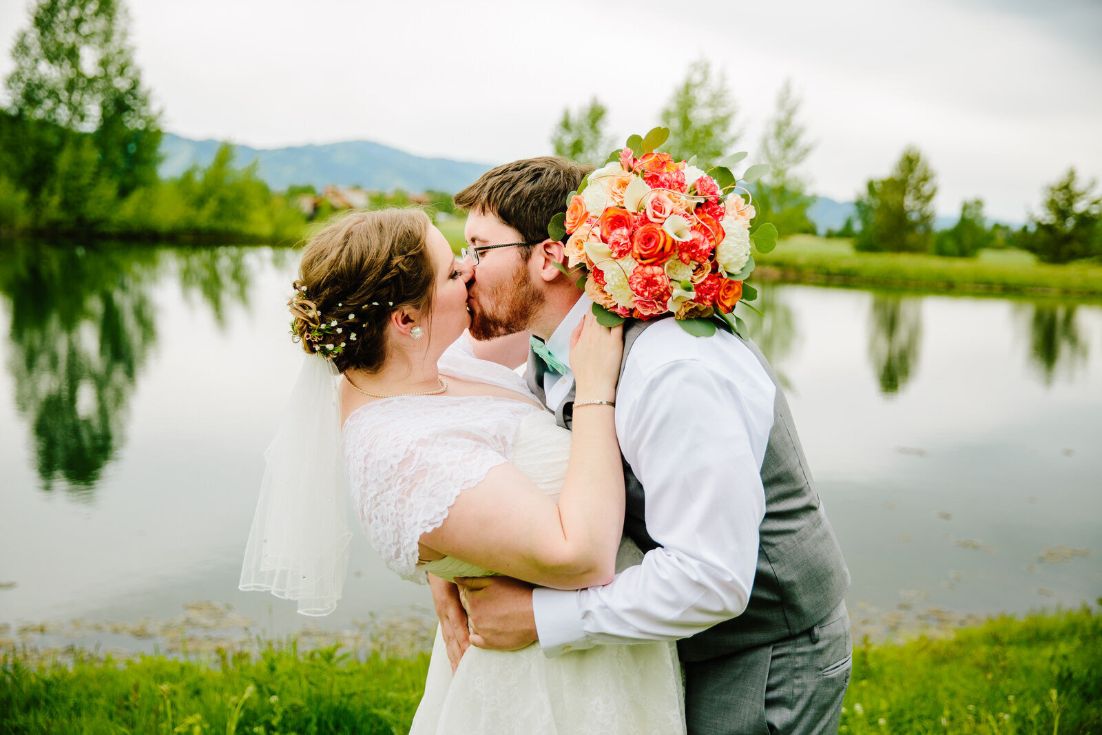 bride and groom kissing beside water during jackson hole photography
