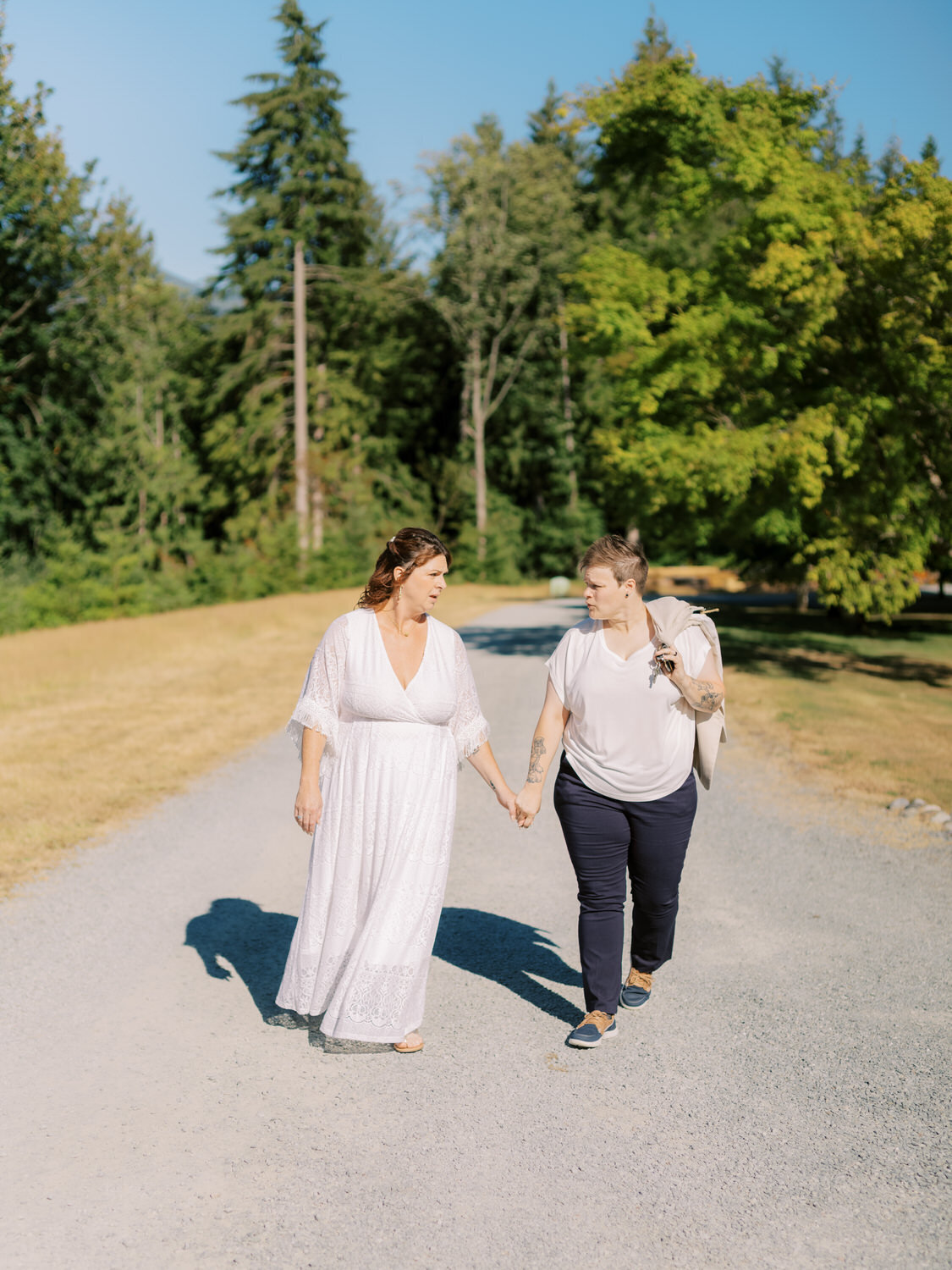 LGBTQ couple hold hands and talk while walking towards the camera