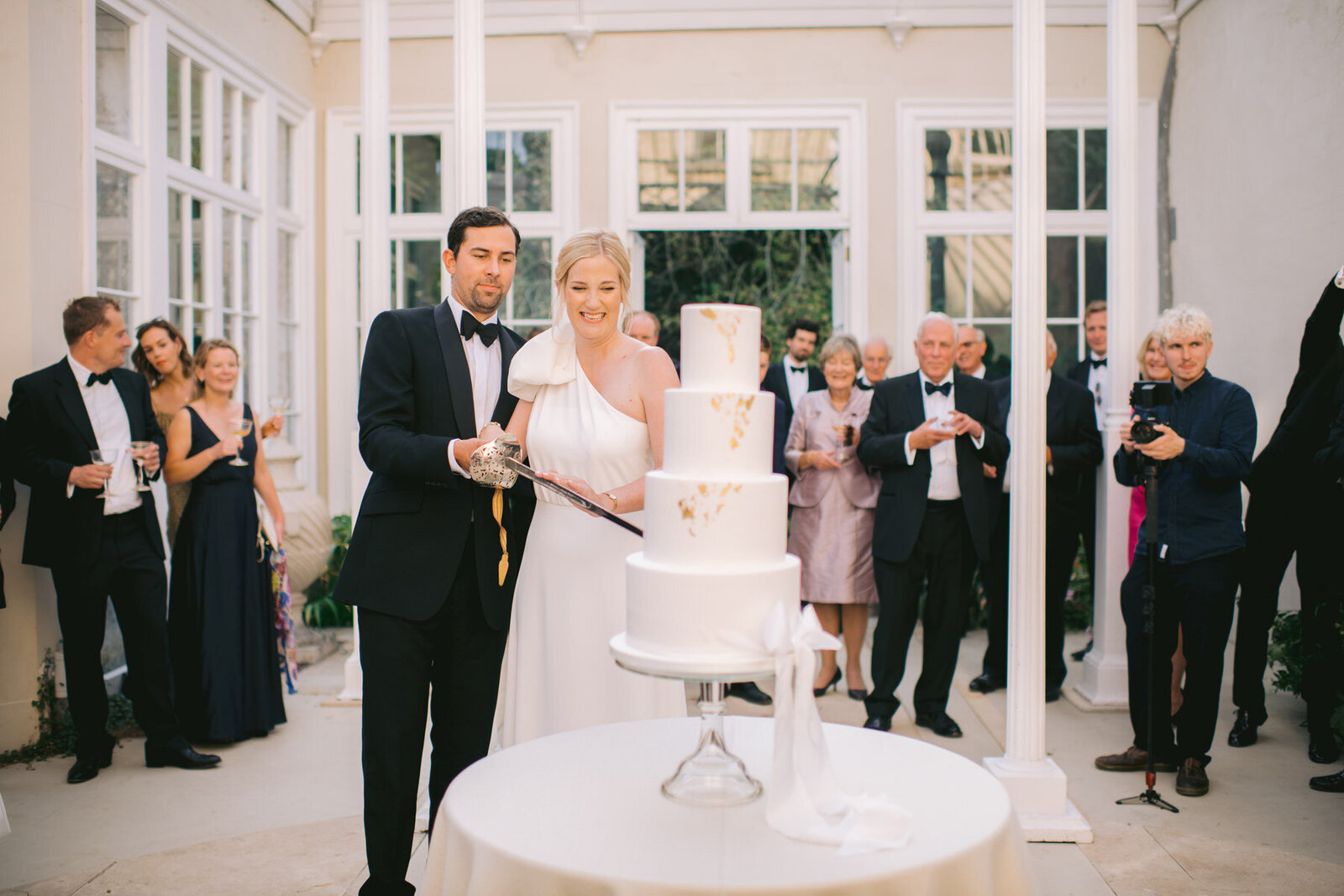 Bride and groom cutting cake  under domed conservatory