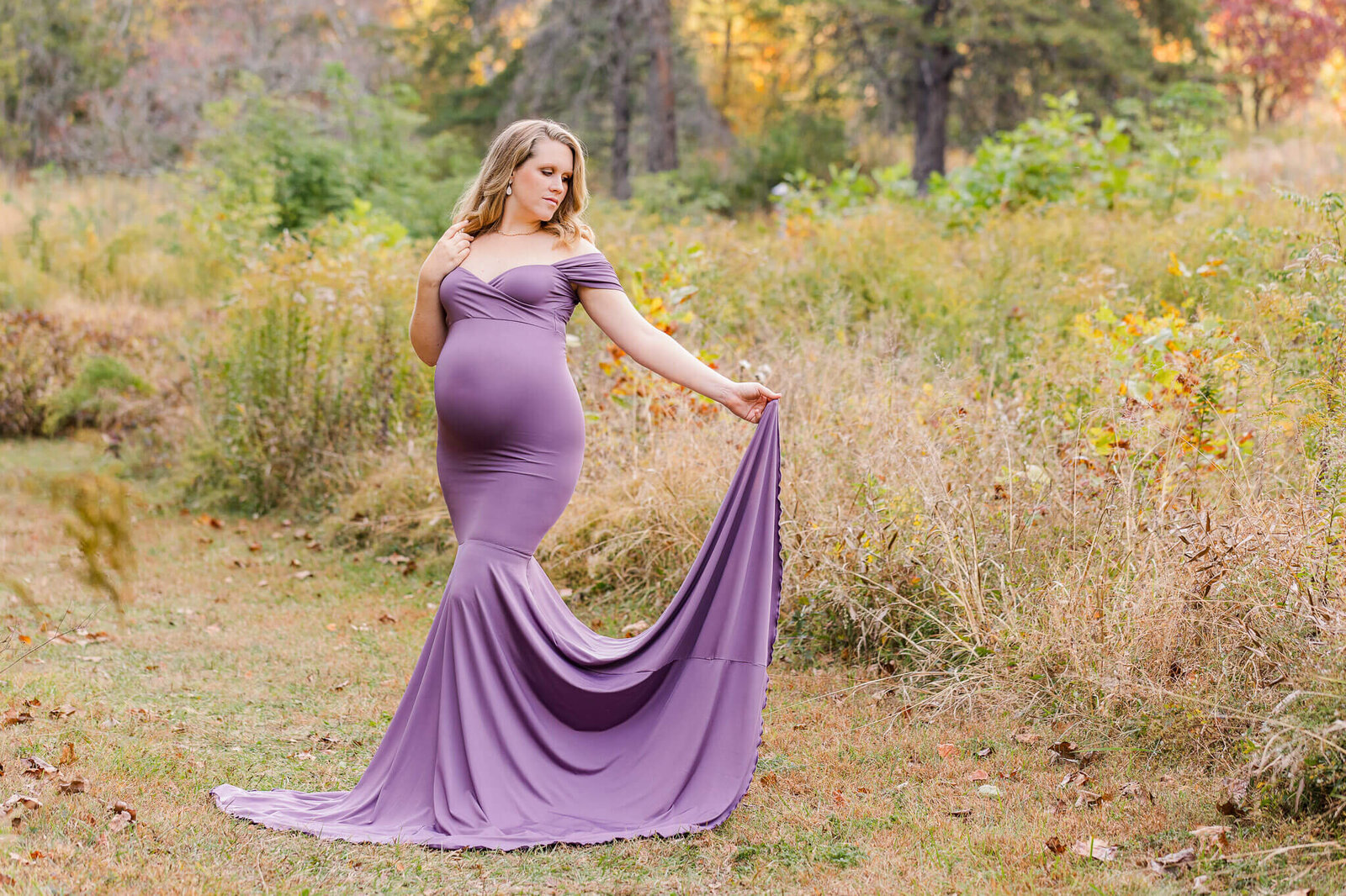 A maternity portrait of a woman in a purple dress in a field in Centreville.