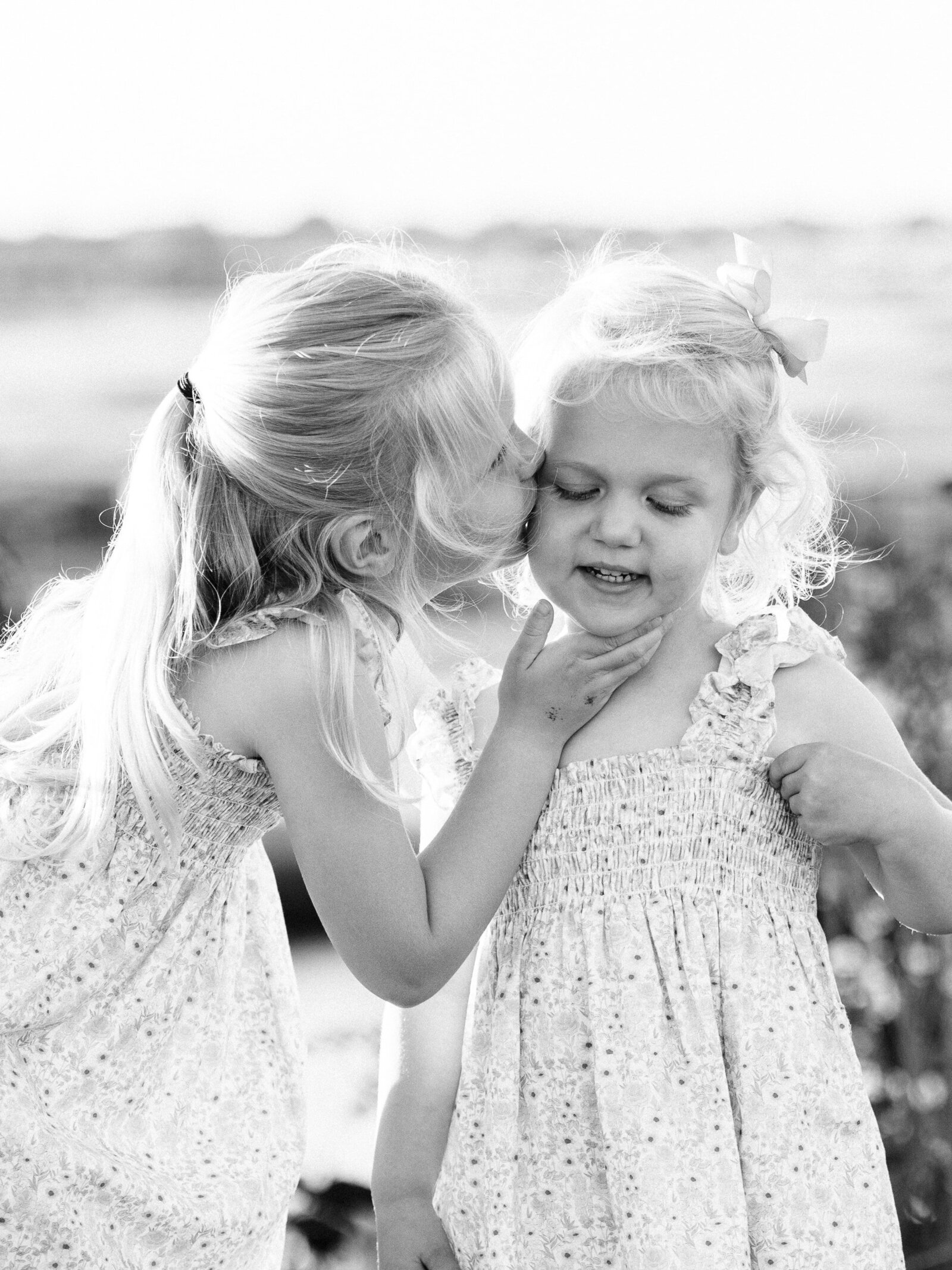 sister kissing cheek black and white