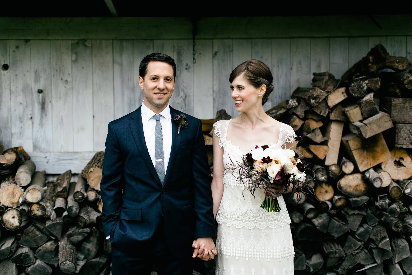 bride and groom at barn wood pile