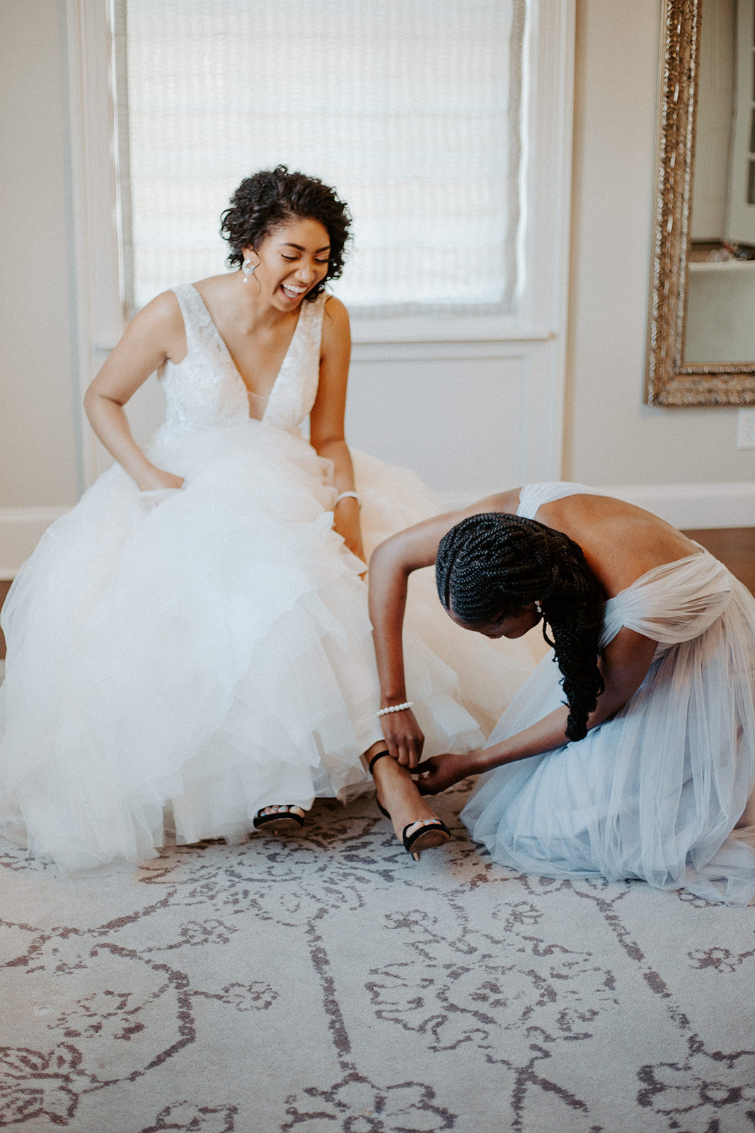 Bridesmaid helping the bride put on her shoes  during his Minneapolis wedding day