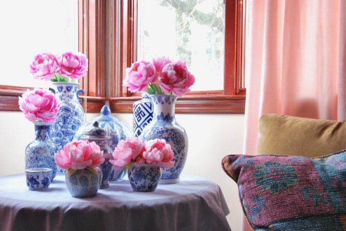 A round table with several blue and white vases with pink flowers.