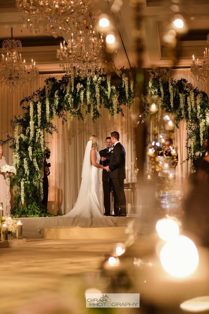 Bride and groom take their vows beneath a lux floral arch