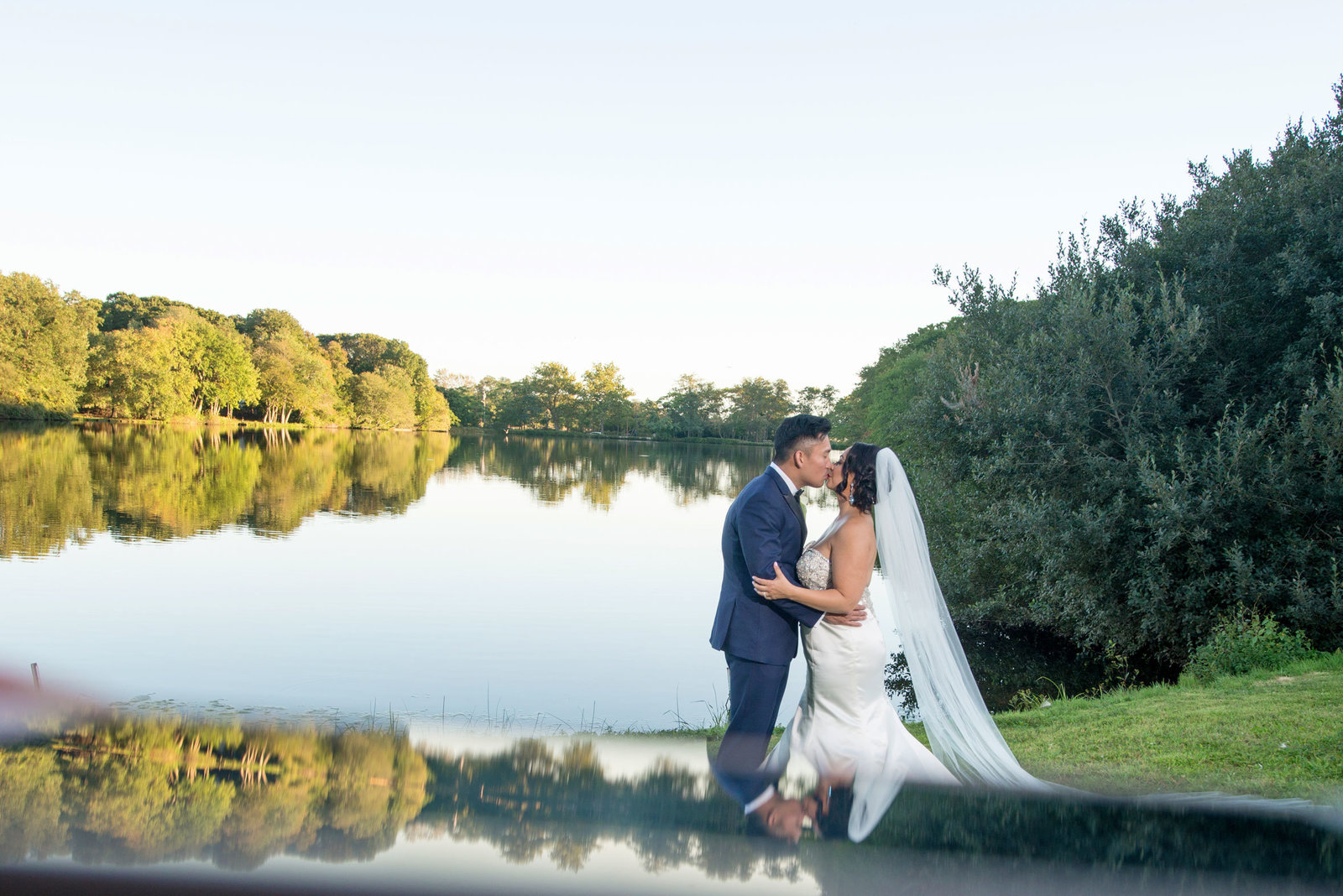 Bride and groom kissing by water at Camp Pa-Qua-Tuck