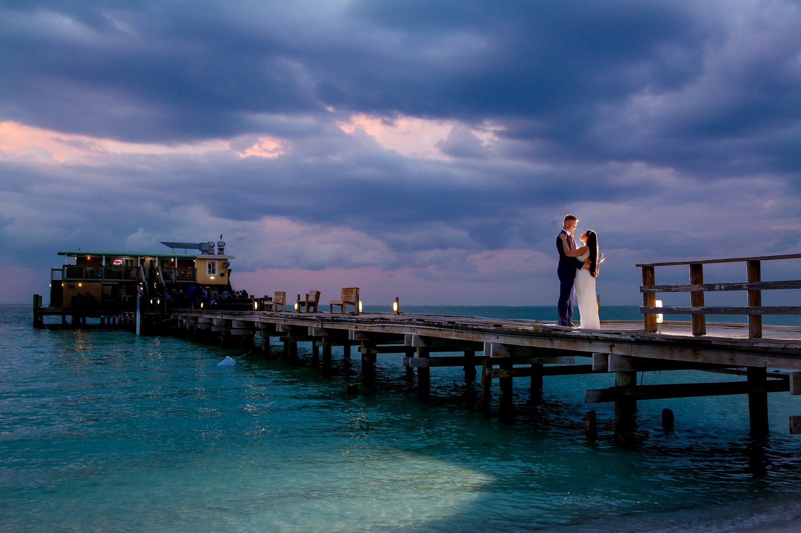Rod and Reel Pier at Sunset with bride and groom on pier backlit