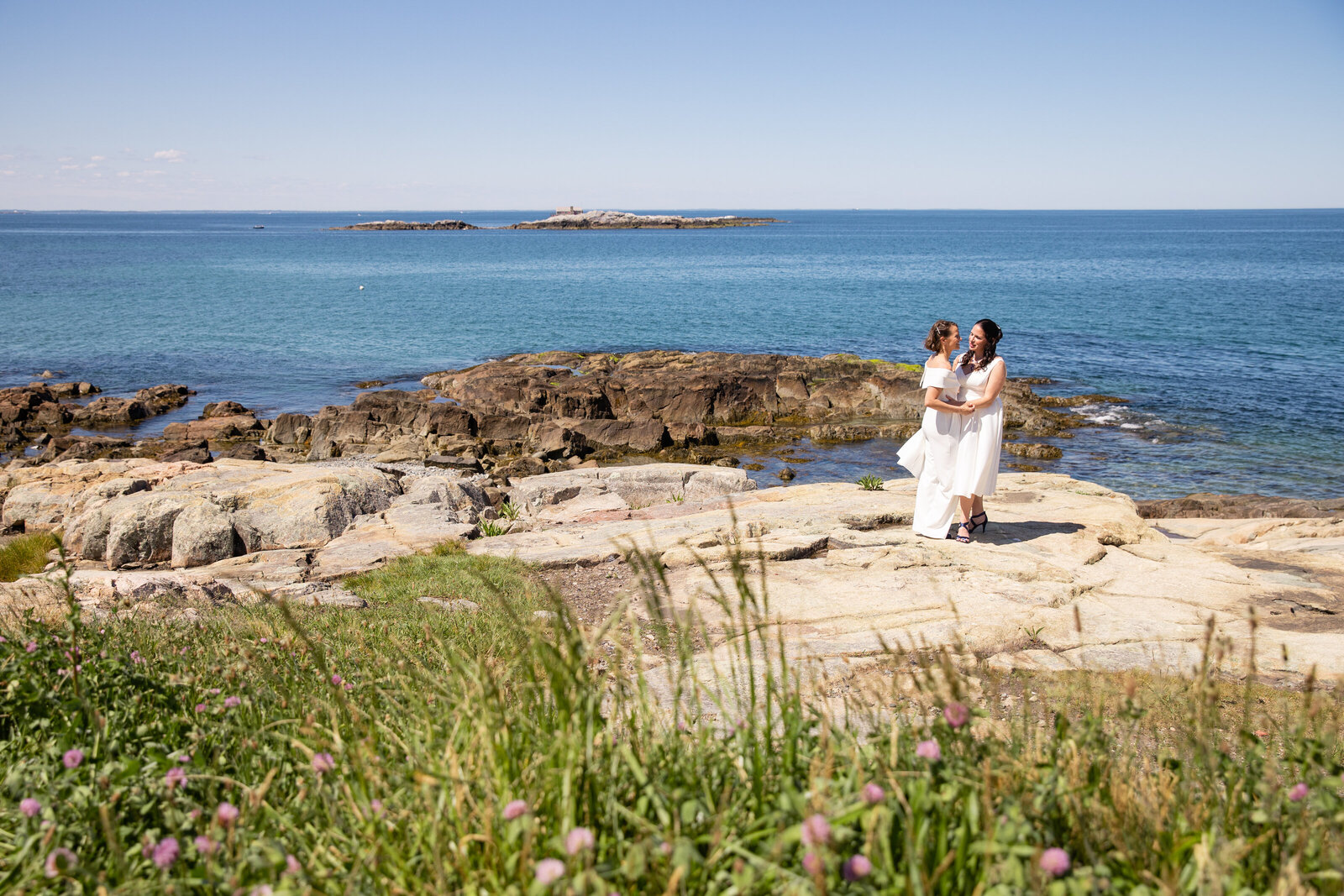 two brides posing on coastal rocks cohasset