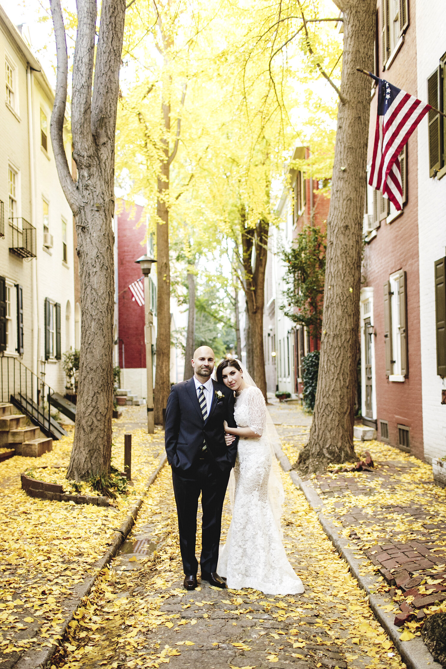 bride and groom with yellow fall leaves on city street