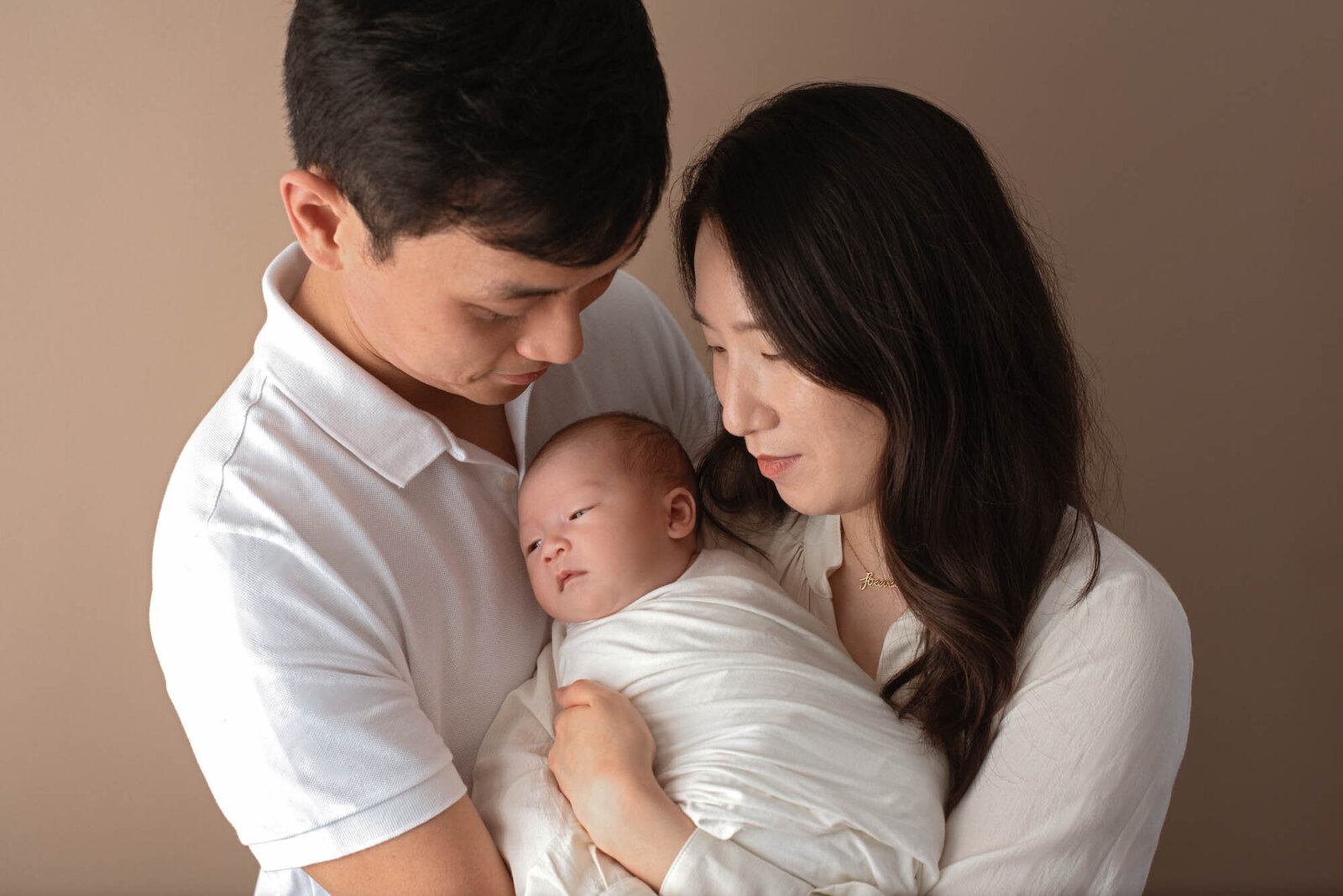 Studio portrait of family holding newborn baby girl