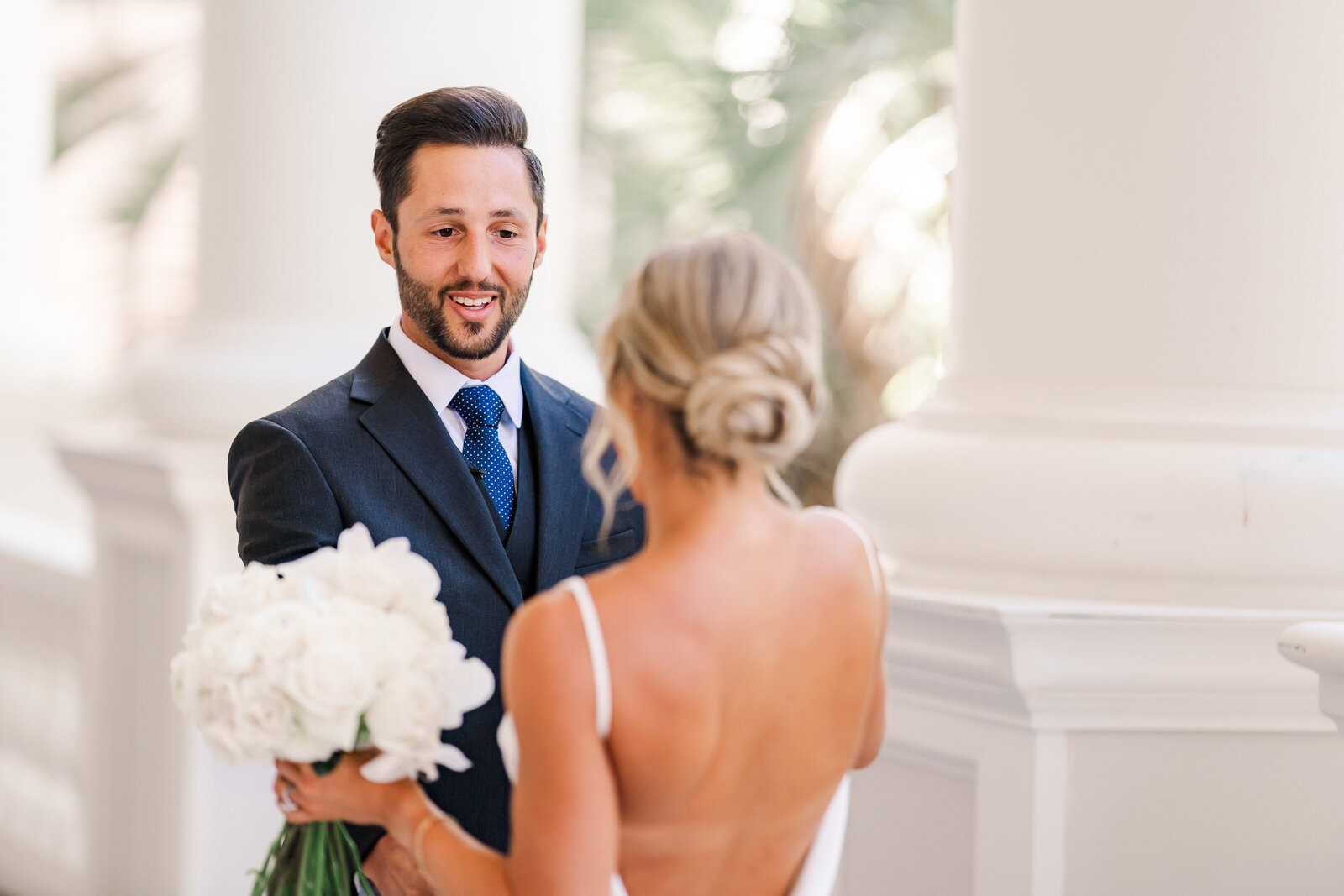 Groom sees bride for the first time on their wedding day with a white backdrop