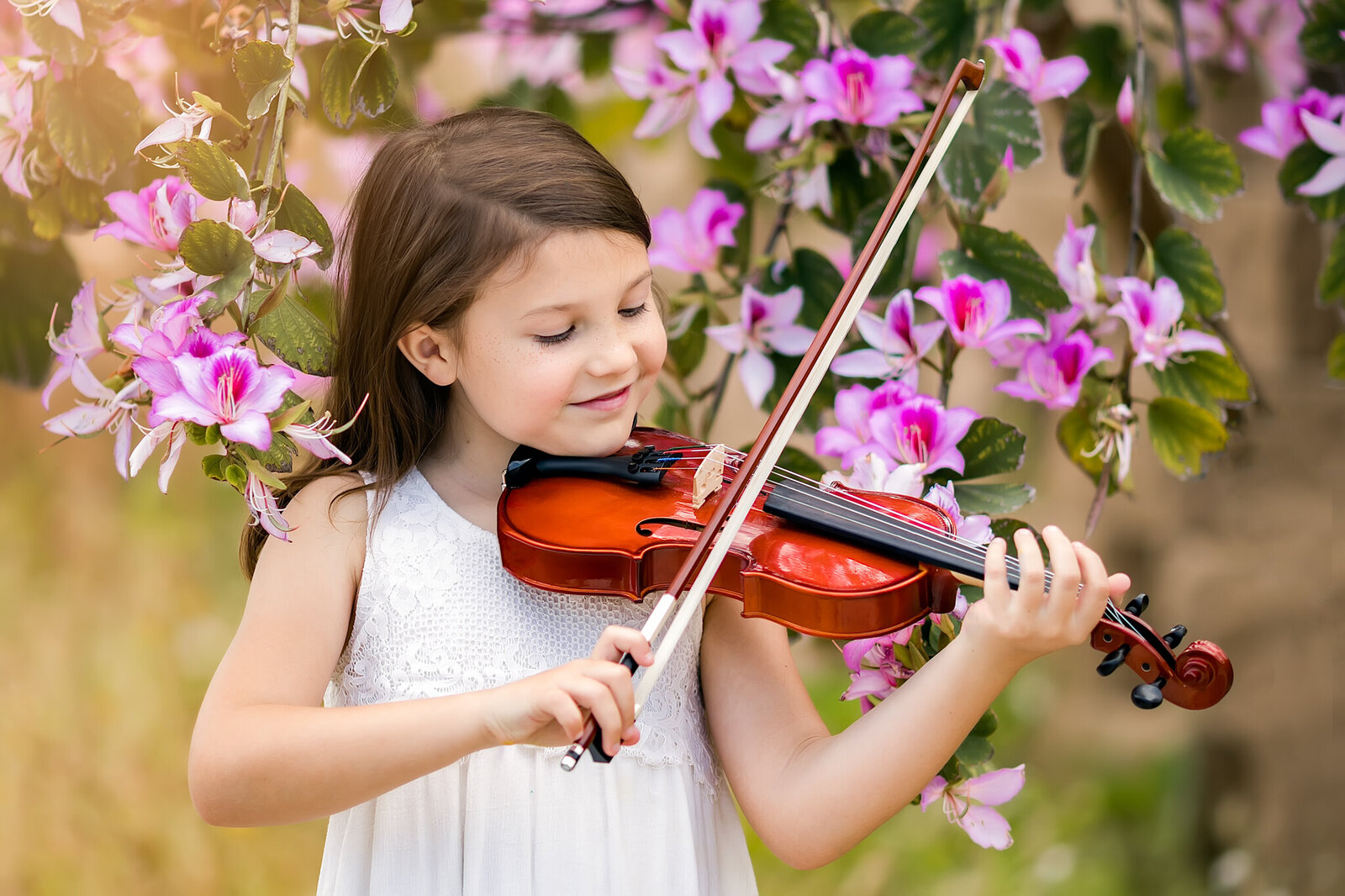 Girl playing violin near a flowering tree