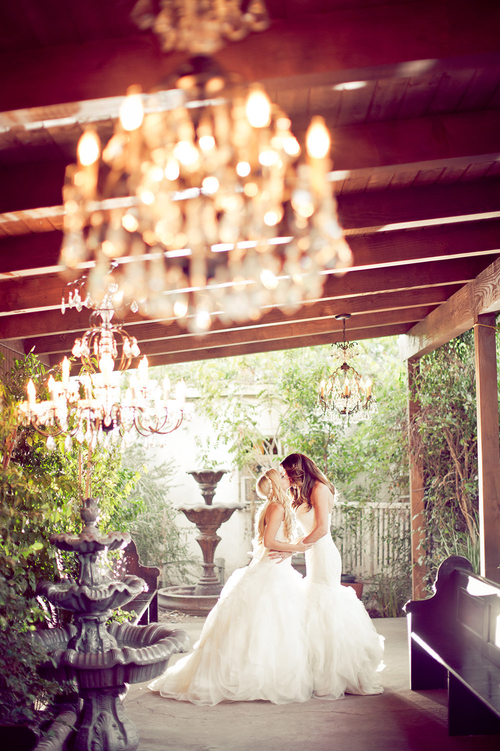 Romantic moment between two brides under chandeliers at Twin Oaks Garden Estate