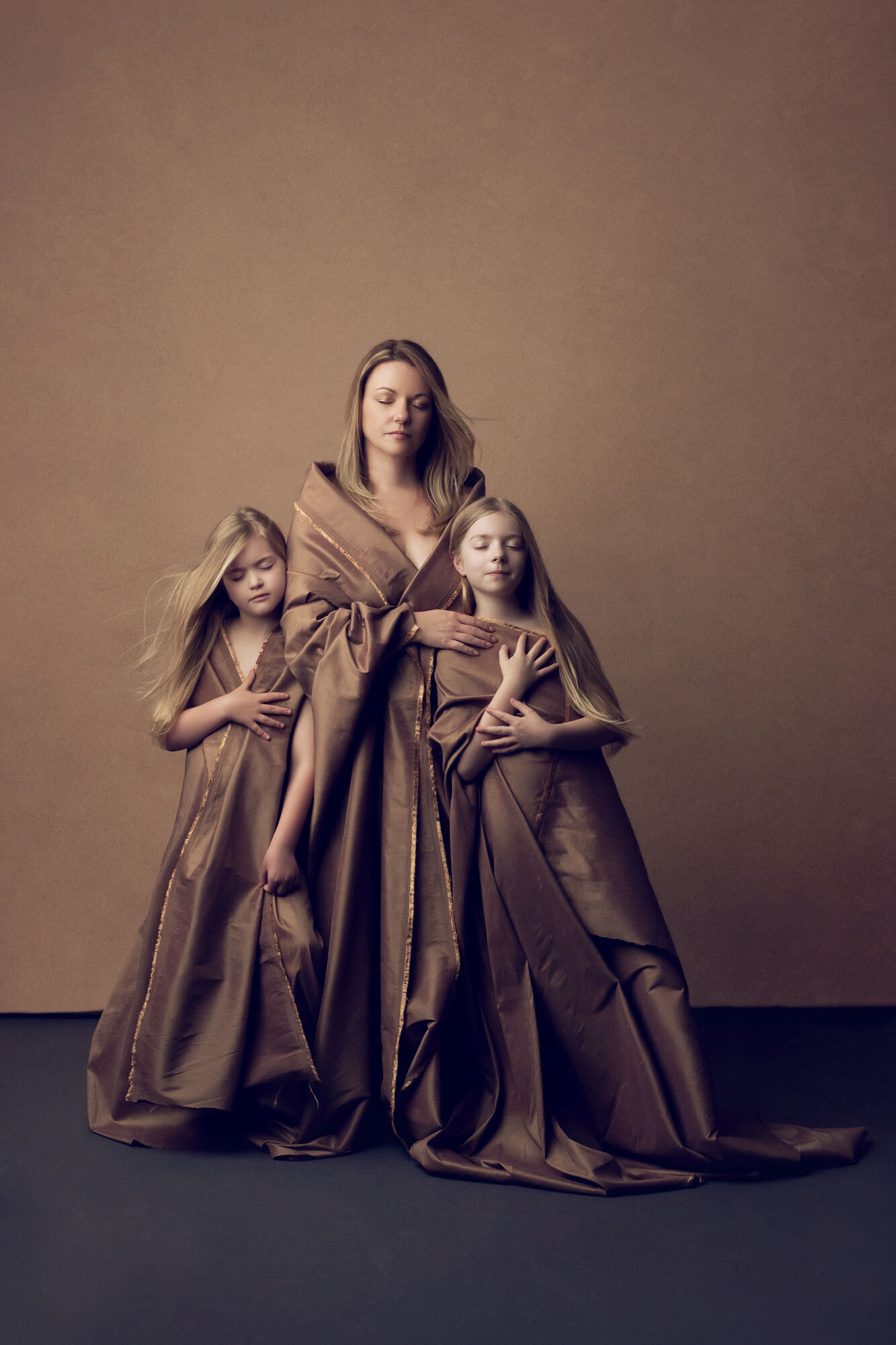 Mother and daughters wearing a silk sheet for a portrait. Houston Fine Art Portraits.