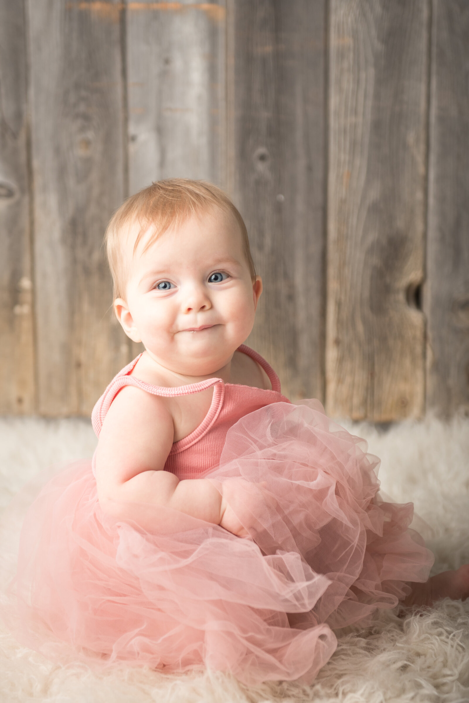 Infant sitting up in pink tutu dress smiling at Always Images in Plymouth Indiana