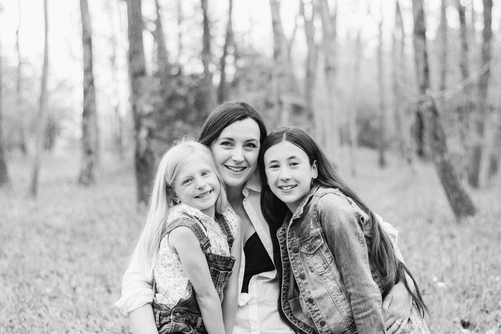 Mum and two daughters smiling in the woods at billingshurst family photoshoot
