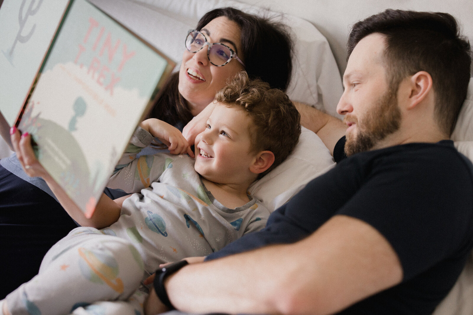 Family reads together in bed during family session