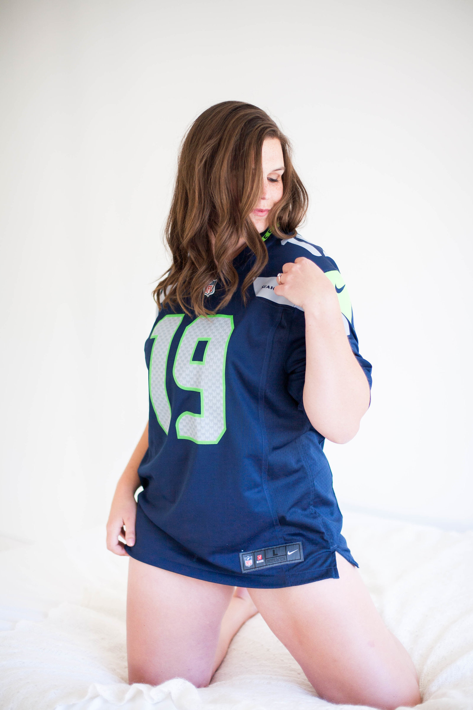 A classy boudoir photo of a woman in a Seahawks jersey.