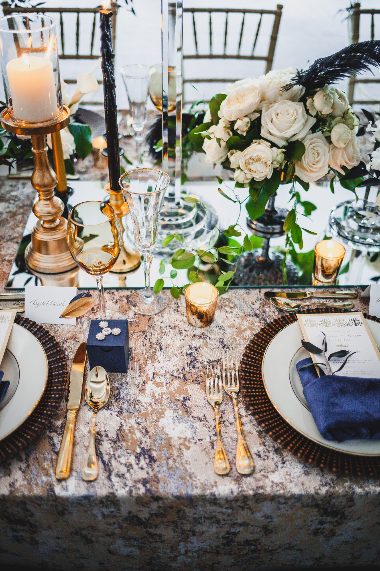 Wedding reception table that has dinnerwares, glasses, candles and floral centerpieces