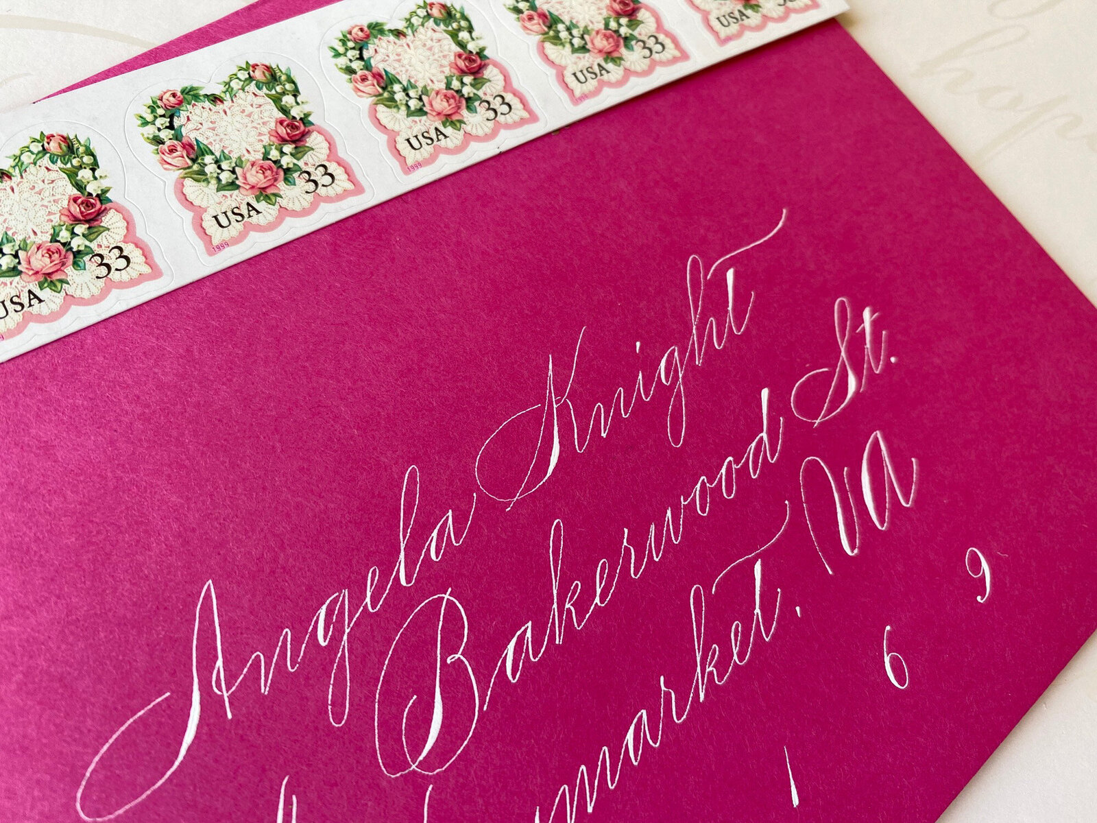 Pink envelope with custom calligraphy and stamps