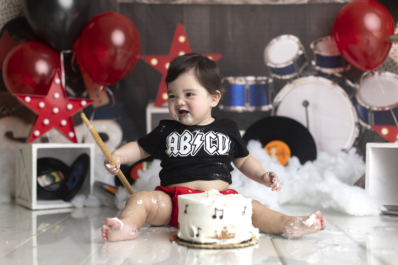 Boy at rock and roll cake smash holding drum stick