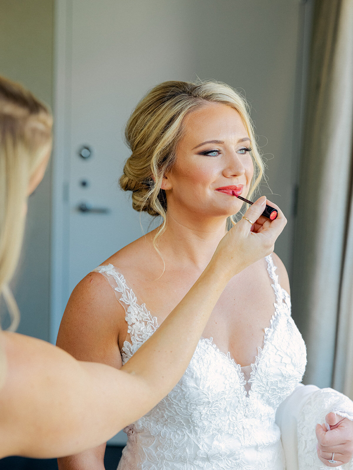 bride getting ready for her wedding day with her bridesmaids and putting on lip gloss