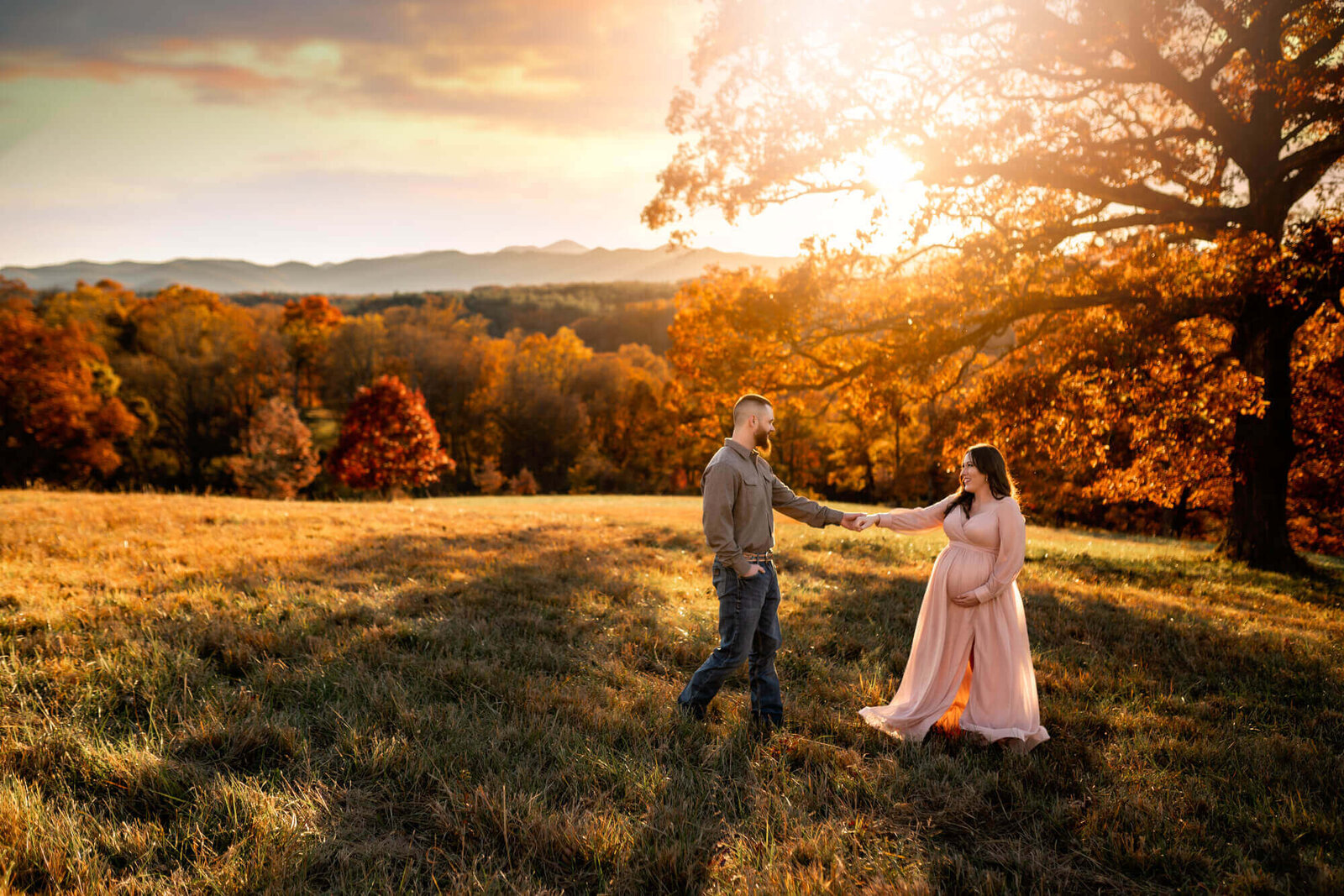 A pregnant couple dancing in the sunlight at an Asheville Family Photographer's photo session
