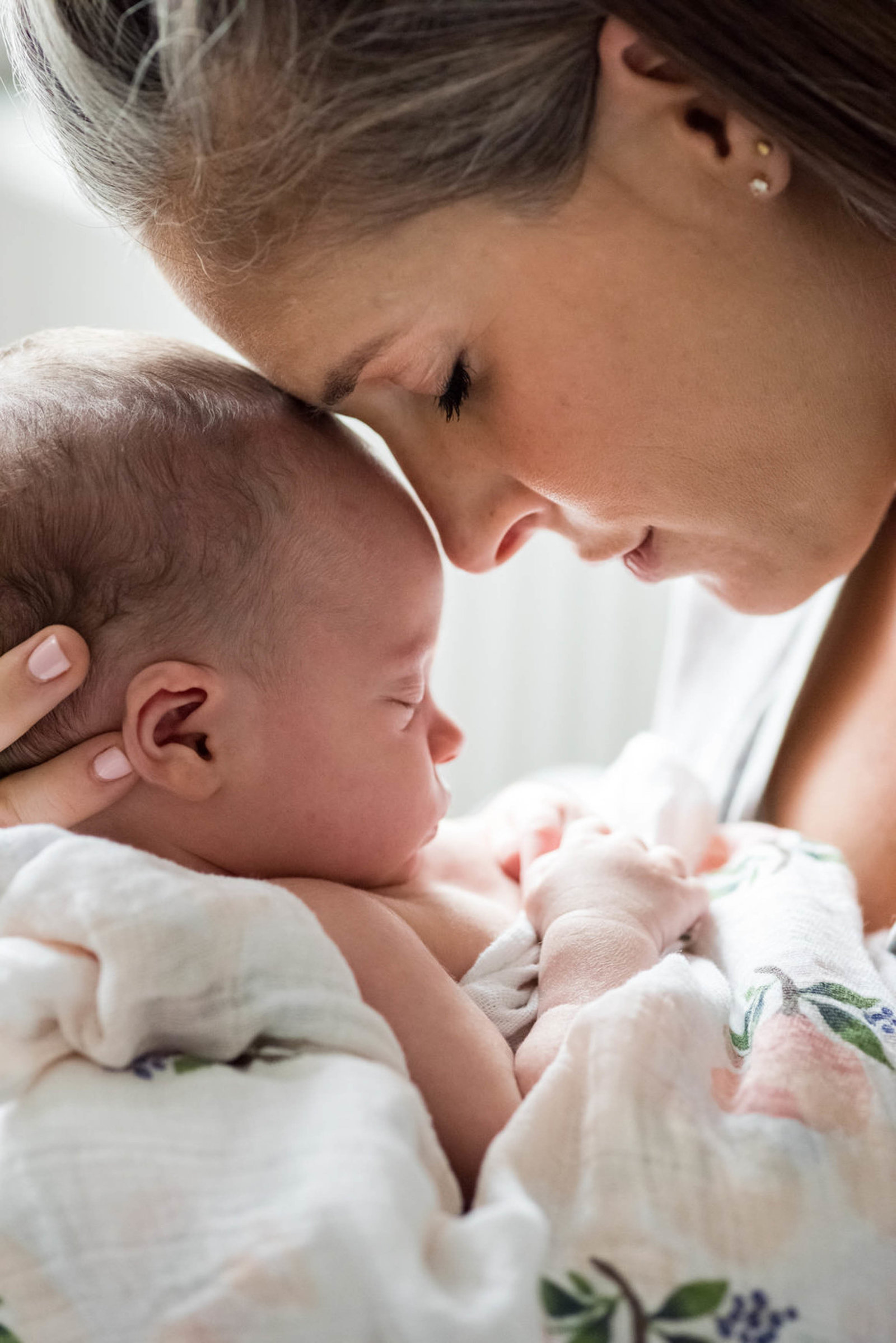 Mom comforts Newborn in arms at home lifestyle Boston Session