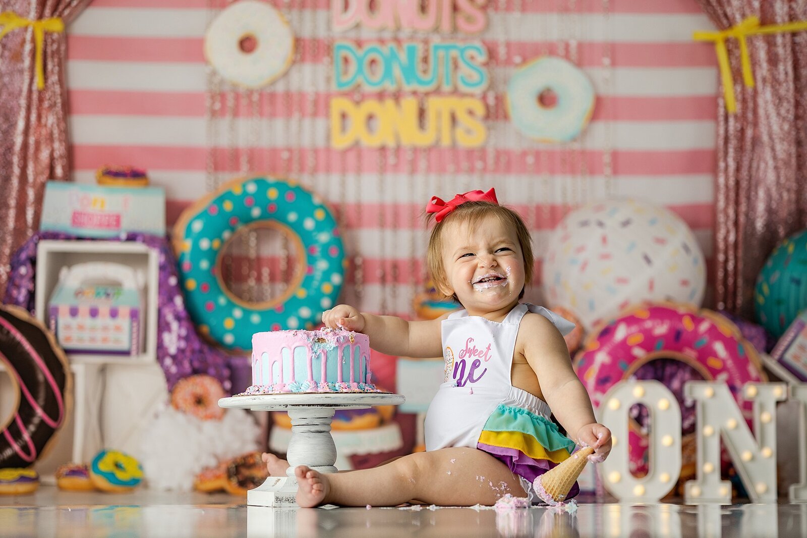 baby girl smiling with her donut cake smash in the quad cities.