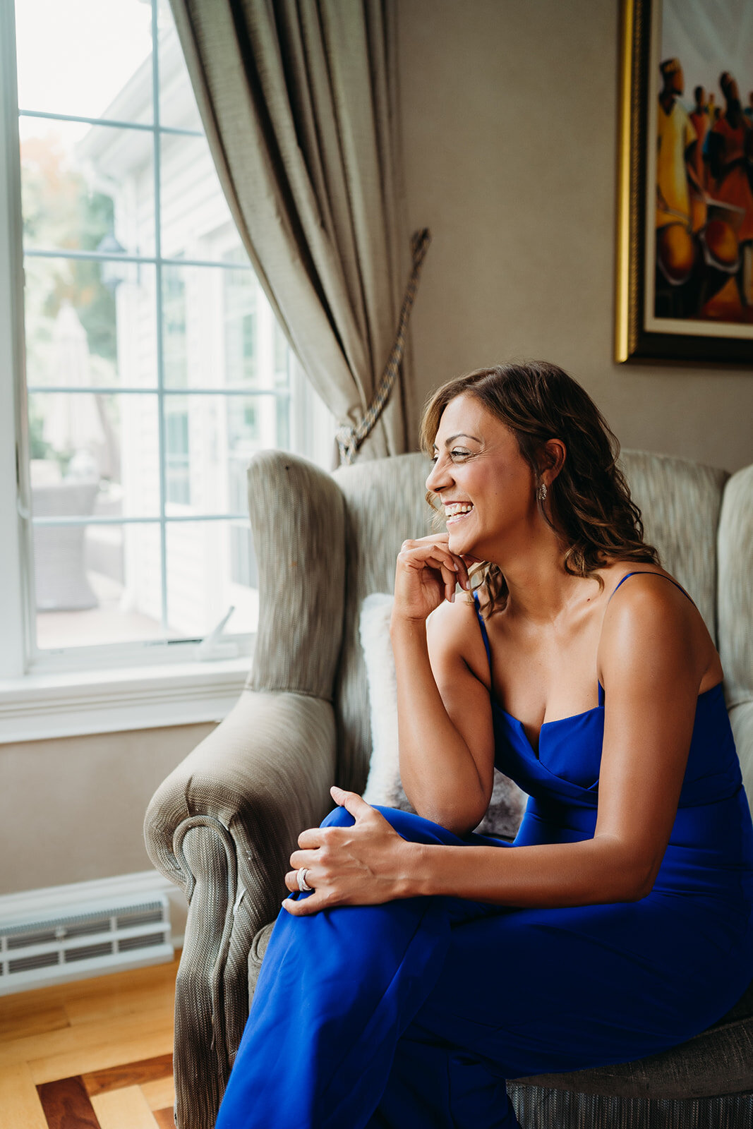 woman in blue jumpsuit looks out window and smiles