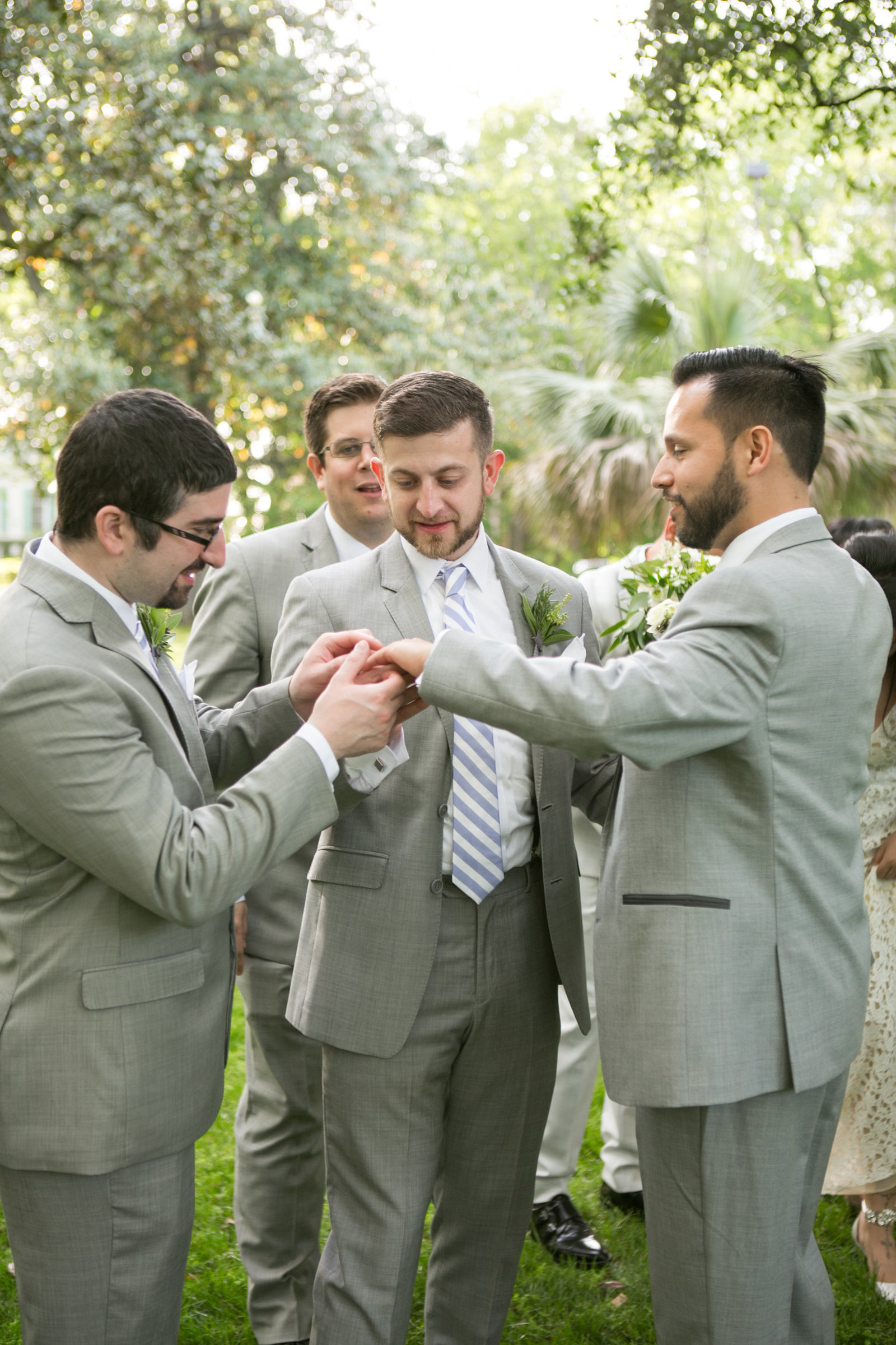 groomsmen holding hand of groom and looking at his new wedding band