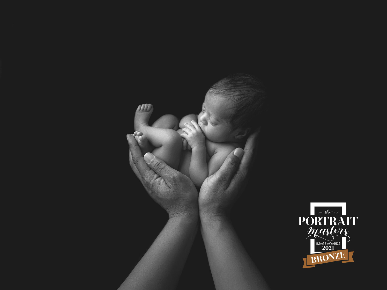 black and white newborn image of baby in parents hands
