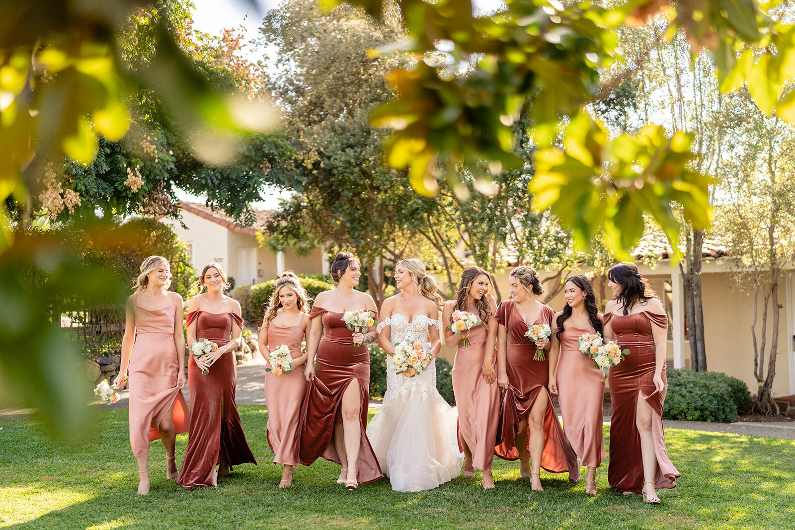 A bride and her bridesmaids walking together on a green lawn at The Inn at Rancho Santa Fe