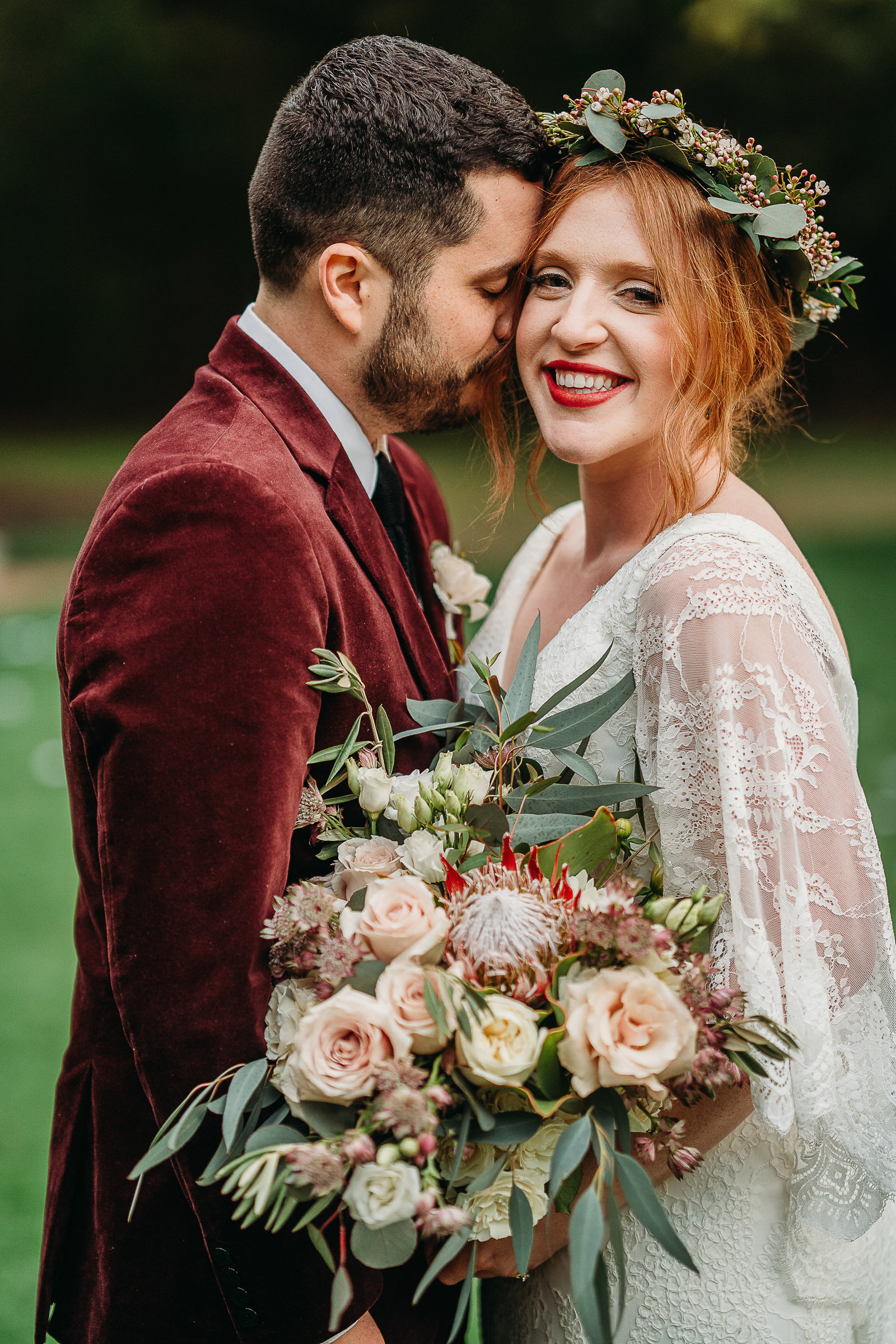 groom in red velevet kisses the cheek of boho bride in boston elopement