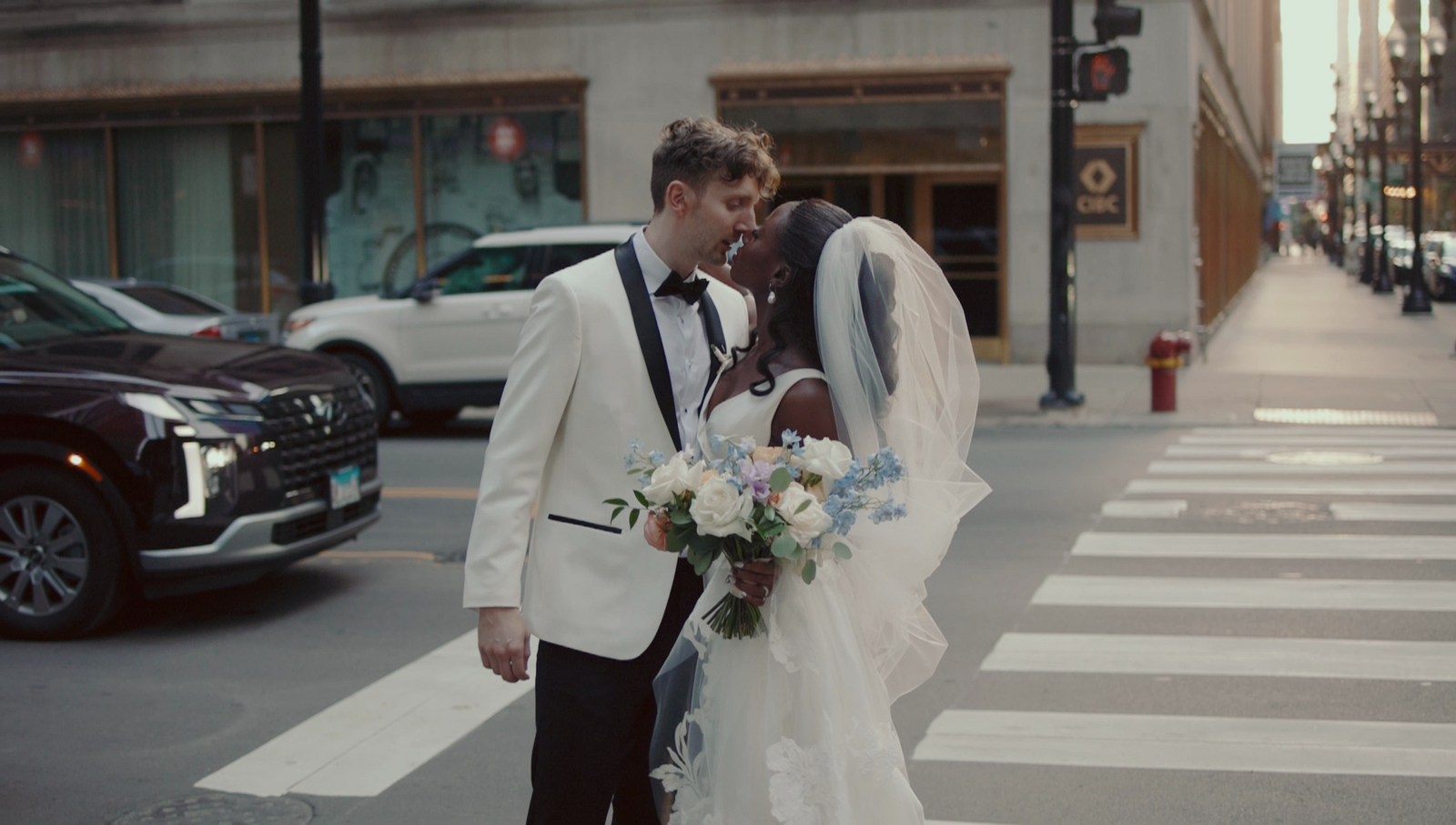 a newlywed couple kiss at a crosswalk in downtown Chicago, IL