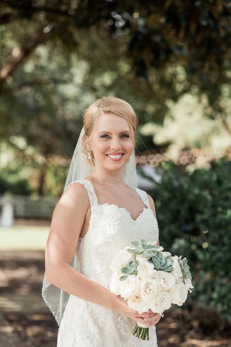 Bride stands underneath trees, Alhambra Hall, Mt Pleasant, South Carolina. Kate Timbers Photography.