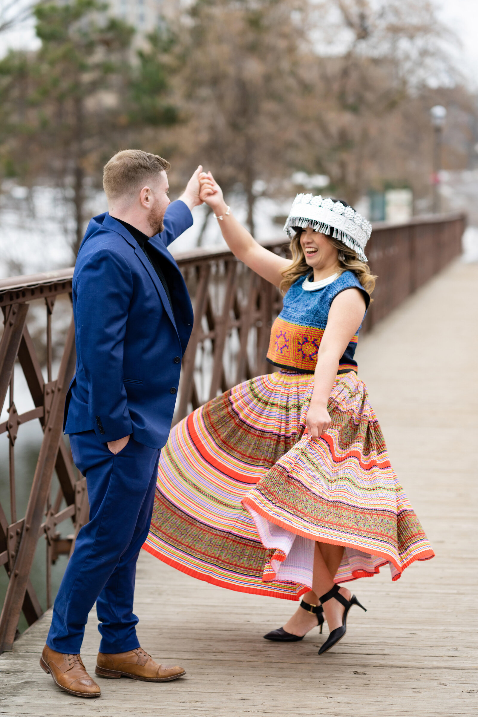 Hmong woman and man in blue suit dance on bridge in Minneapolis, Minnesota.