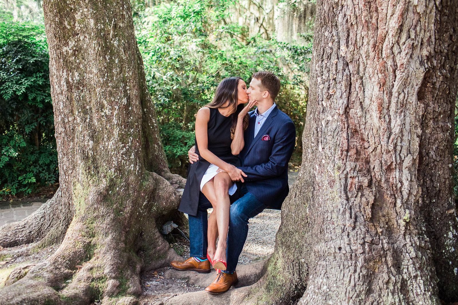 Engaged couple sit on a natural bench between two trees, Magnolia Plantation, Charleston, South Carolina