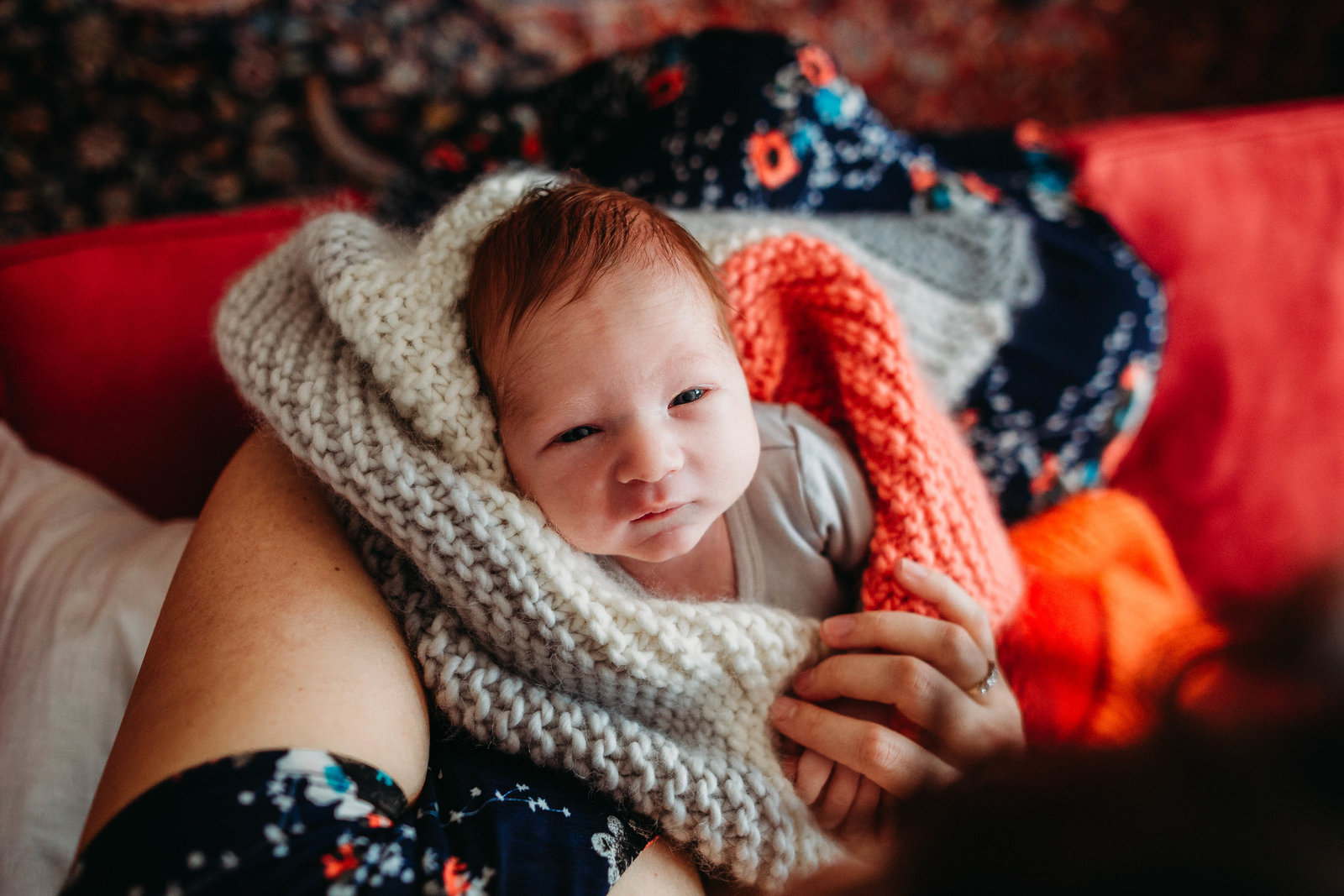 redheaded newborn baby wrapped in colorful knit blanket during cambridge newborn session