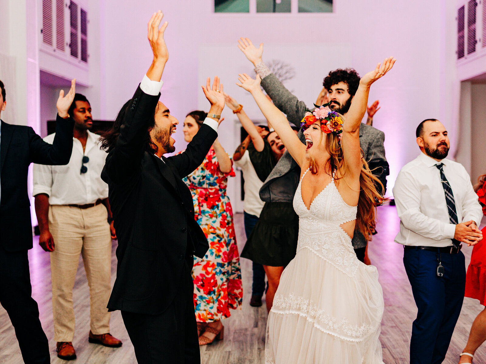 A bride and a groom dance to the YMCA during their wedding reception. The image, taken by wedding photographer KD Captures, also features some of the couple's guests dancing as well.