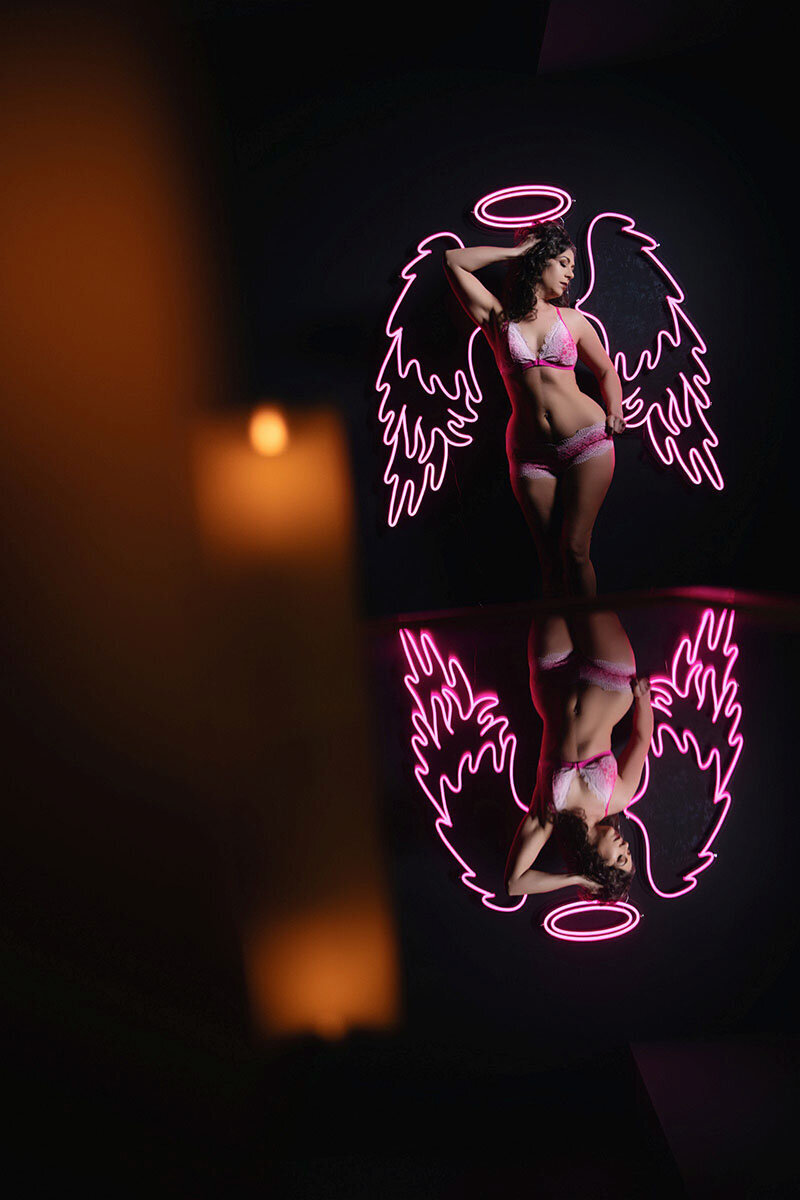 Woman posing infront of pink neon wings and halo