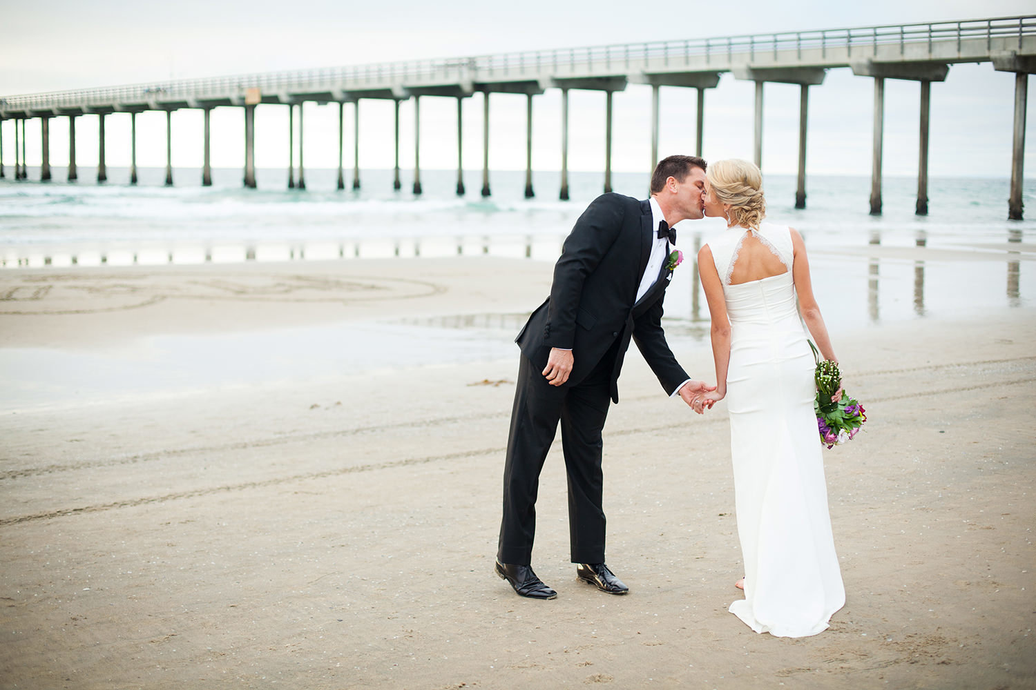 bride and groom kissing with scripps pier in the back ground
