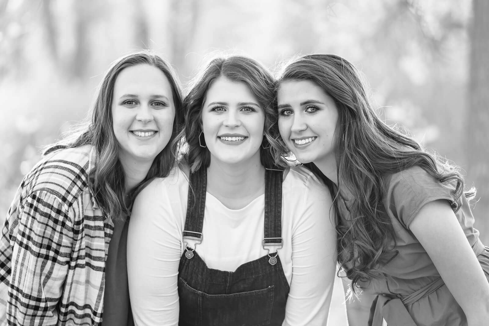 B&W salt lake photography of a closeup of three teenage sisters leaning in close to each other at Arrowhead Park in Murray