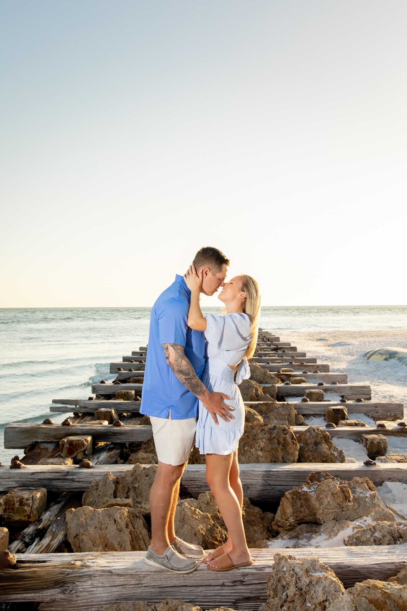 Recently engaged couple kissing on the jetty at Coquina Beach Park