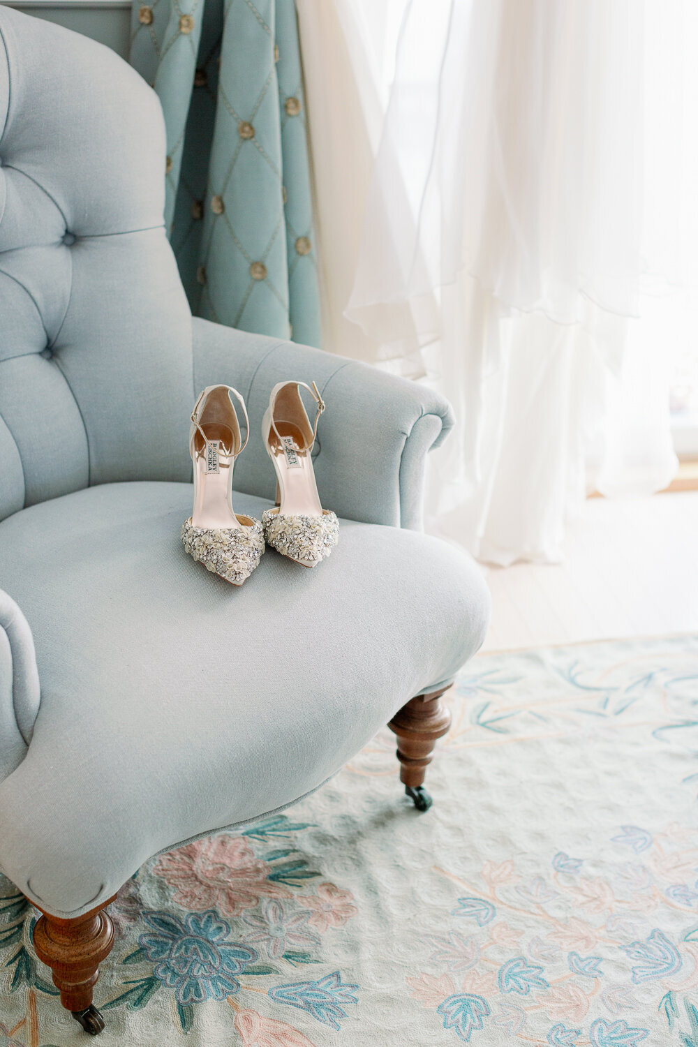 A pair of heels sitting on a plush blue chair.