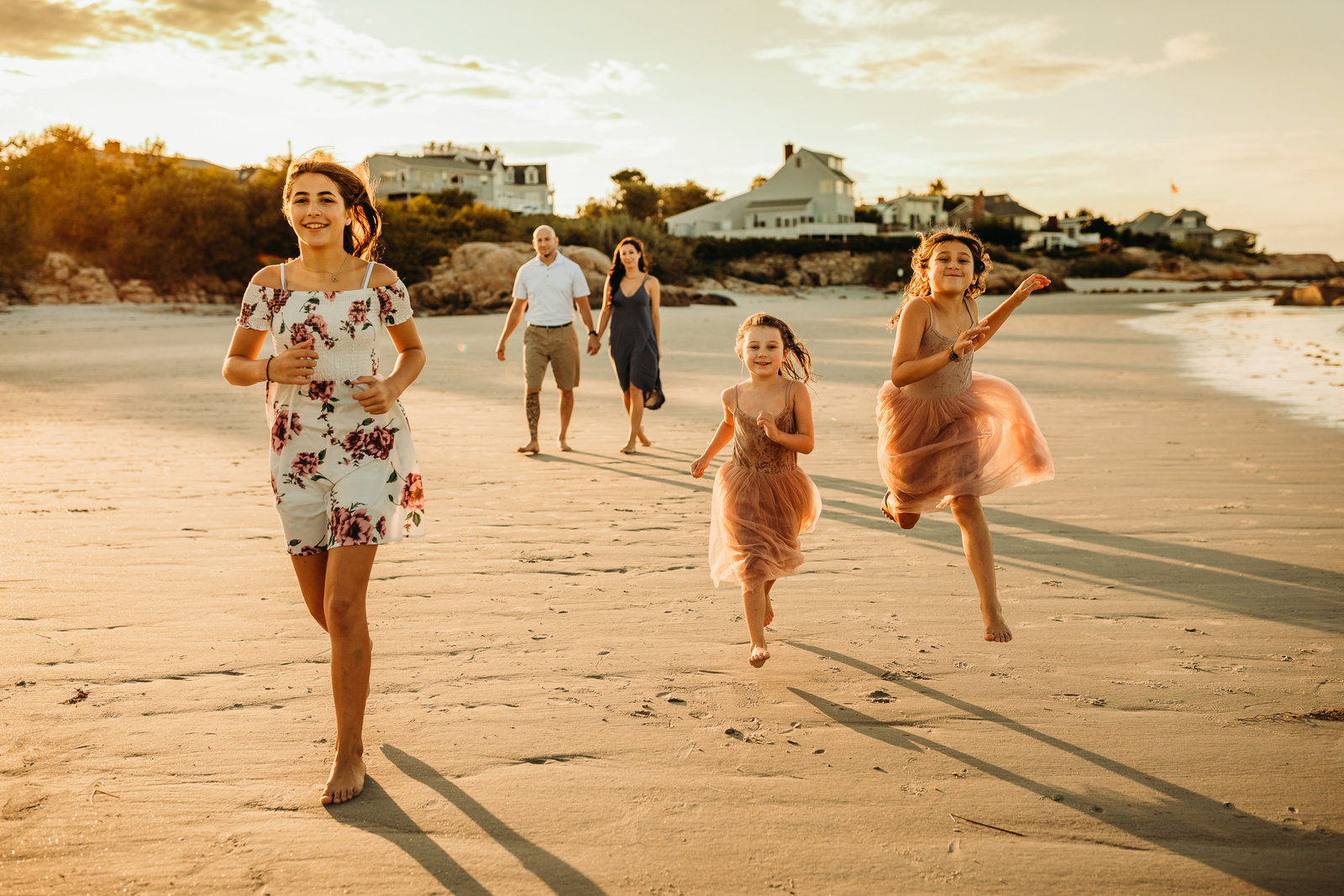 three sisters run towards camera on beach during family session on north shore boston